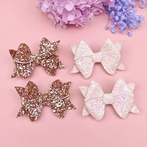 Detailed view of layered glitter hair bows in brown and pink on a soft floral surface