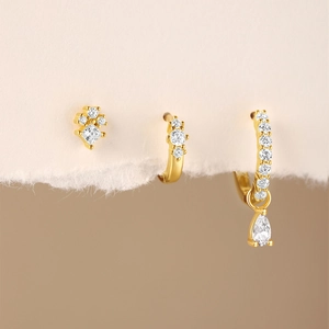Macro detail of gold-plated silver earrings with white zircon and geometric drop design