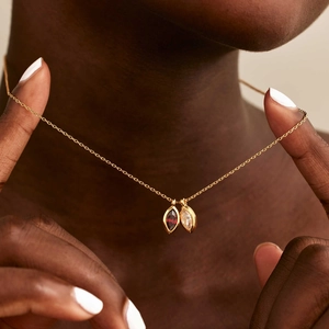 Close-up of gold necklace with red and white marquise zircon birthstone pendants