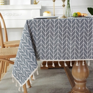 Close-up of grey cotton linen tablecloth with white arrow pattern and decorative tassels