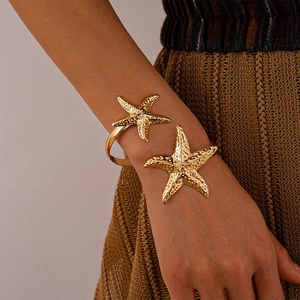 Close-up of golden starfish open arm cuff with realistic texture on a woman wrist
