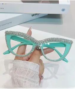Dettaglio occhiali da sole cat-eye verde menta con strass argentati su tavolo bianco