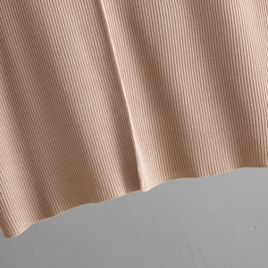 Close-up detail of premium beige ribbed knit fabric showing vertical texture and drape