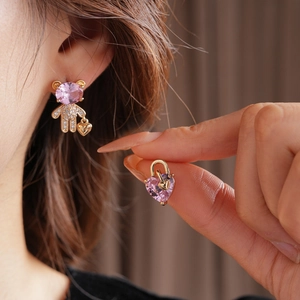 Detail view of model wearing pink zircon bear and heart mismatched gold earrings