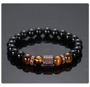 Macro detail of men's tiger eye beads and rose gold cubic zirconia charms on bracelet