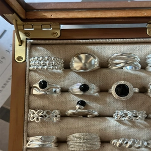 Adjustable silver rings set with black onyx gemstones in a wooden jewelry box