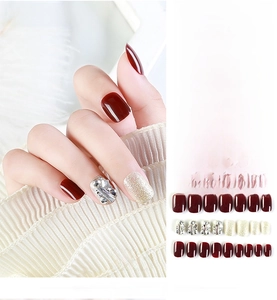 Close-up of handmade deep burgundy press-on nails with silver glitter and rhinestones