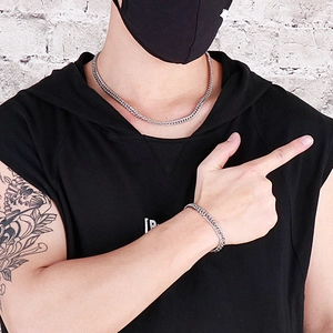 Close-up of men's silver Cuban link chain necklace and bracelet set on a street model
