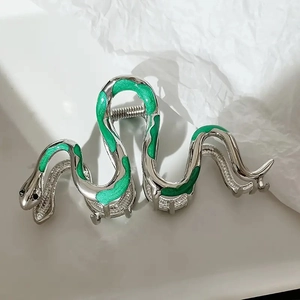 Detailed view of silver snake hair claw clip with emerald green enamel inlay details