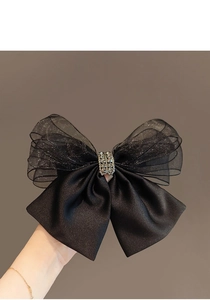 Detail of a black mesh bow hair clip with satin fabric and sparkling rhinestone center
