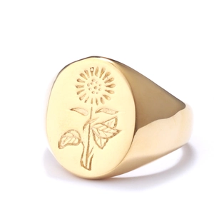 Macro detail of engraved sunflower on a vintage polished golden stainless steel signet ring