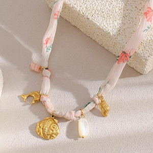 Detail of 18K gold-plated ribbon necklace with pink floral fabric and shell charms