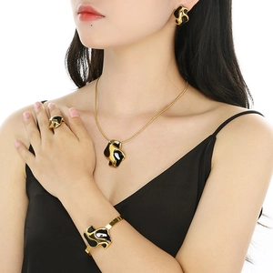 Detail of gold and black enamel flower jewelry set worn by a model on white background