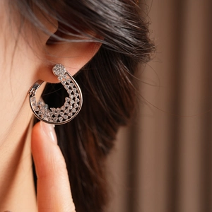 Close-up of a silver-plated flower hoop earring with pavé zircon stones on a model's ear