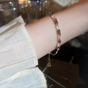 Detail of adjustable rose gold bracelet with purple rectangle and round zircons on wrist
