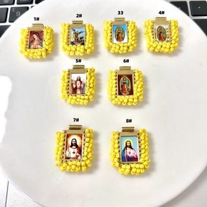 Macro detail of eight handcrafted religious charms with yellow beads in a white dish