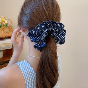 Detailed view of a navy blue polka dot scrunchie styled on a low ponytail