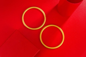 Detailed view of two matte gold minimalist bangles on a luxury red velvet display
