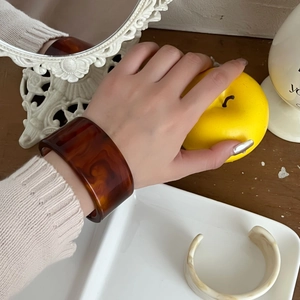 Nahaufnahme von unregelmäßigen Acetat-Armreifen in Schildpatt und Creme am Handgelenk