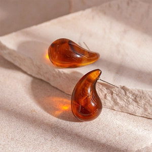 Gros plan de boucles d'oreilles goutte en résine ambre avec tiges en argent fin