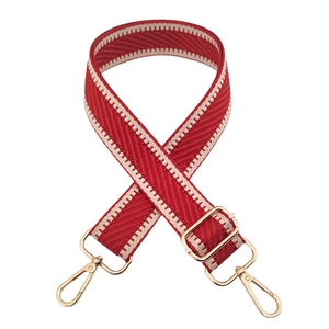 Detail of red and white chevron woven bag strap with golden metal clasps on white background