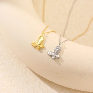 Detailed macro shot of gold and silver butterfly pendants with fine engraved textures