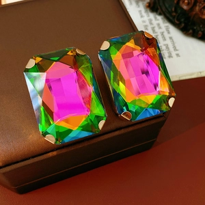 Macro shot of rectangular iridescent crystal earrings in a golden four-claw setting
