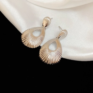 Detailed macro shot of teardrop earrings featuring metallic radial texture and hollow design