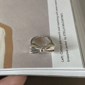 Macro detail of silver bow ring with adjustable band on fashion magazine background