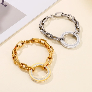 Close-up of gold and silver thick chain bracelets with crystal encrusted round ring charms
