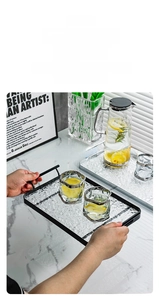 Close-up of a rectangular metal serving tray with water-ripple glass and dual handles