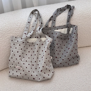 Detailed view of canvas tote bags with red polka dots and bow patterns on textured sofa