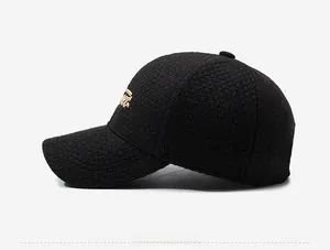 Détail d'une casquette de baseball noire texturée avec broderie de lettres dorées sur le côté