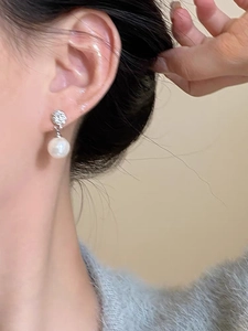 Detail of elegant 925 silver pearl drop earring worn on ear with zircon accents