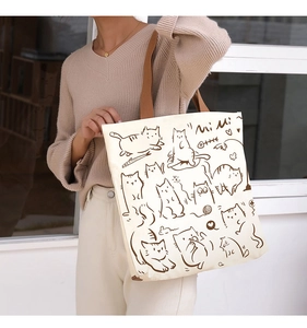 Detail of canvas tote bag with brown cat illustration and Mi Mi script on model
