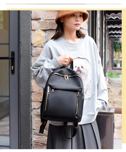 Outdoor shot of a black nylon backpack for women with gold zippers and multi-pocket detail