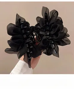 Makro-Detail einer großen schwarzen Chiffon-Haarklammer mit eleganten Rüschen aus Organza