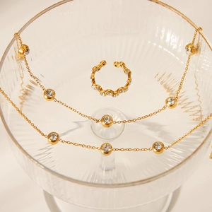 Detailed view of 18K gold plated jewelry set with sparkling zircon on a glass tray