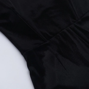 Gros plan sur la texture du velours noir et la couture à la taille de la robe moulante