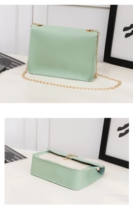 Detail view of mint green crossbody bag with gold chain strap and interior contrast flap