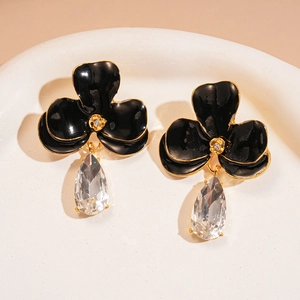 Vue détaillée de boucles d'oreilles fleur en émail noir avec cristal goutte d'eau