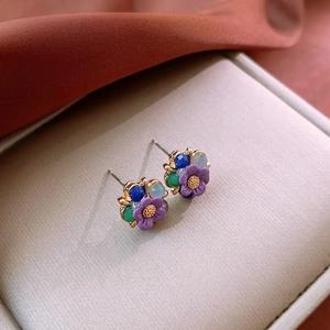 Macro shot of purple flower earrings with multi-colored crystals and golden base