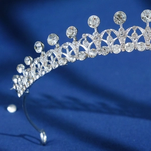 Close-up detail of a silver baroque bridal crown with sparkling rhinestones on blue silk