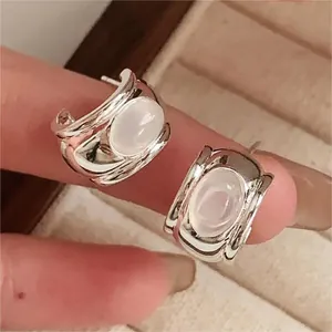 Close-up of minimalist 925 sterling silver stud earrings with oval moonstone inlay