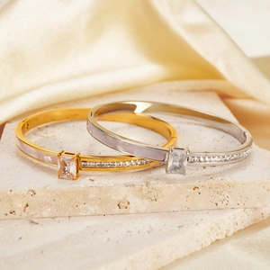 Elegant gold and silver stainless steel bangles with zircon and shell inlay on silk background