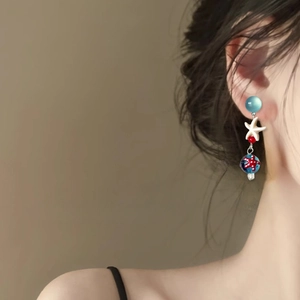 Dettaglio di orecchino a stella marina con perle blu su modella per un look da spiaggia
