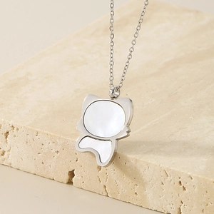 Macro shot of silver fox head pendant with shimmering shell inlay on beige stone
