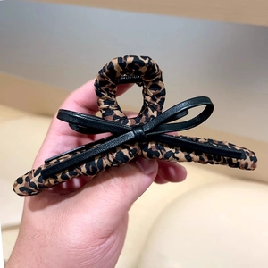 Détail de la pince à cheveux léopard avec un nœud décoratif en cuir noir