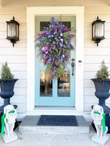 Detailed close-up of a large purple tulip and lilac teardrop wreath on a blue front door