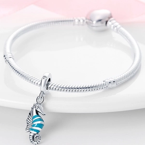 Detailed close-up of a silver seahorse charm with blue enamel and a clear gemstone bead